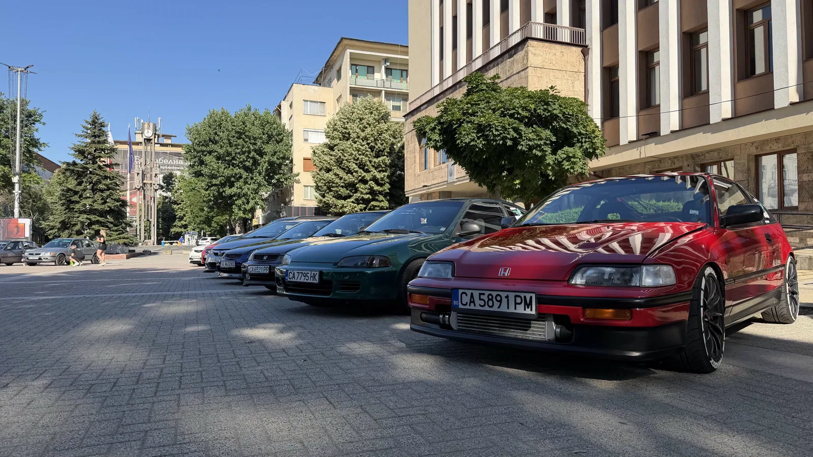 Червена Honda и редица автомобили пред сграда на градски площад на Национална Хонда Среща 2026